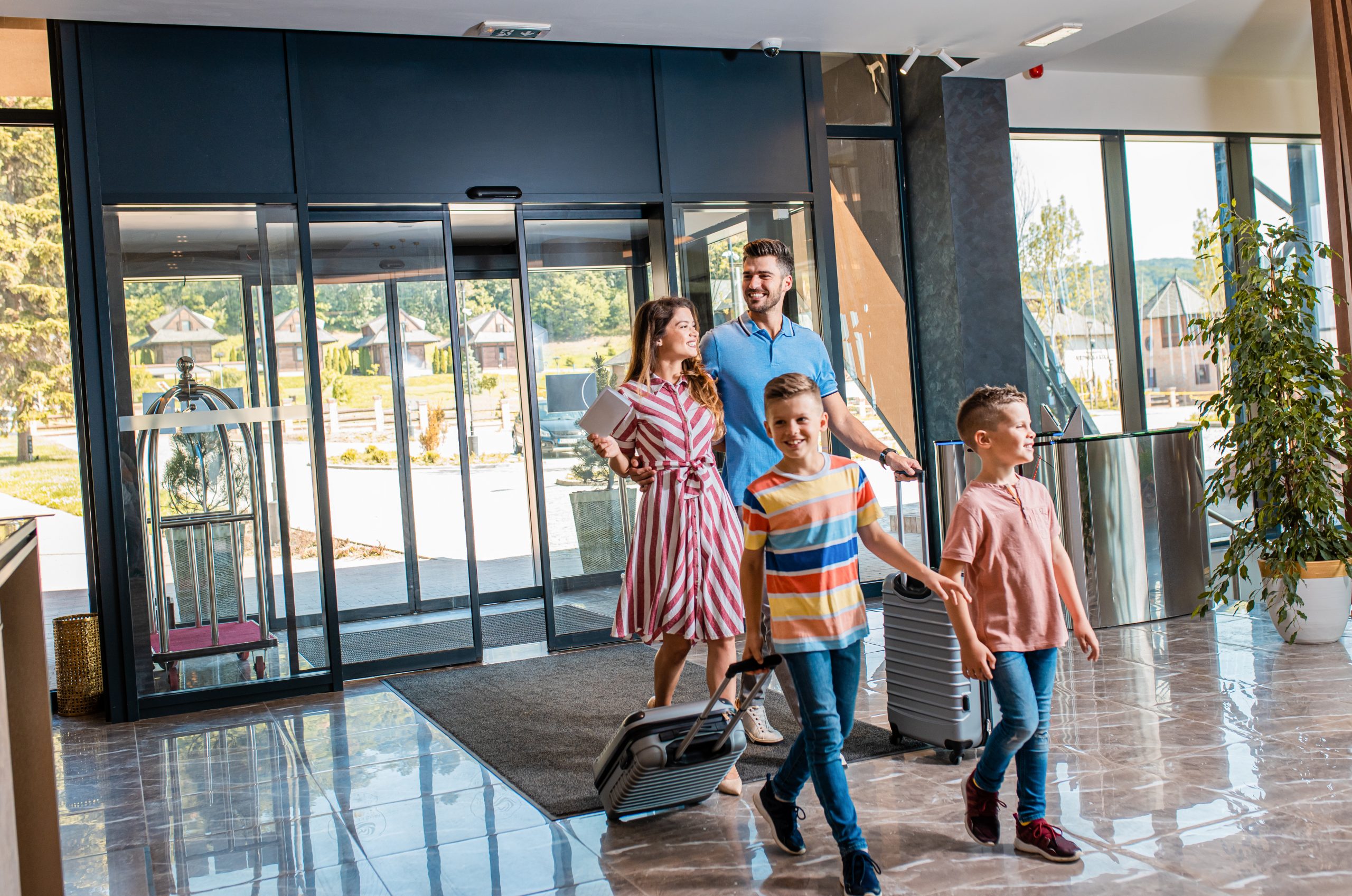 Hotel guests arriving during peak summer travel, representing how personalized loyalty perks and digital signage enhance the guest experience.